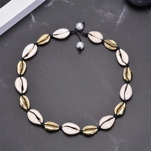 Detail of handcrafted shell necklace with gold accents and pearls on black cord
