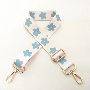Adjustable wide beige shoulder strap with blue floral pattern and gold metal hooks