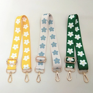 Close-up of adjustable fabric bag straps with daisy floral patterns and gold metal hooks