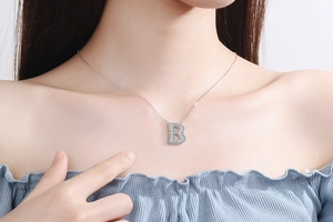 Close-up of sparkling silver letter B necklace with rhinestones on a female model