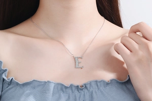 Close-up of letter E pendant necklace with rhinestones on model's collarbone