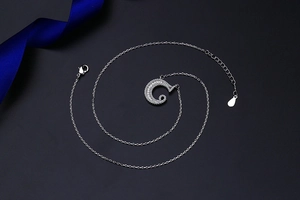 Macro detail of silver C-shaped spiral necklace with micro-pave cubic zirconia crystals