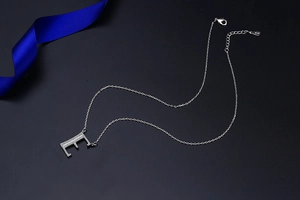 Macro detail of silver S925 letter E necklace with sparkling white cubic zirconia stones