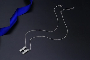 Macro detail of S925 sterling silver chain with H initial pendant and lobster clasp