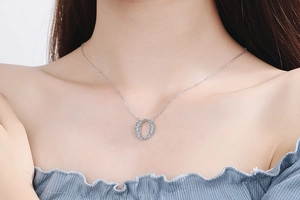 Close-up of a silver-tone oval pendant encrusted with sparkling cubic zirconia on a model