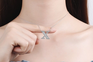 Close-up of silver necklace featuring an X letter pendant with micro-paved zircons