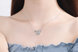 Detailed close-up of a shimmering crystal-encrusted letter W pendant on a silver chain