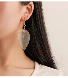 Close-up of vintage golden mesh leaf earrings showing intricate hollow textures on model