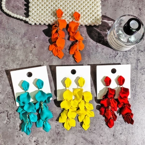 Flat lay of colorful tiered petal earrings in orange, blue, yellow, and red with matte finish