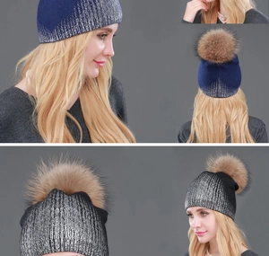 Detail of dark blue and black knit beanies with silver glitter and large fur pom-poms