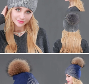 Detail view of metallic glitter knit beanie with large fur pom-pom in grey and navy