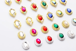 Macro detail of oval alloy nail charms with colorful rhinestones in gold and silver frames