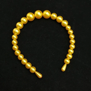 Macro detail of golden handmade beaded headband with gradient size faux pearls on black velvet