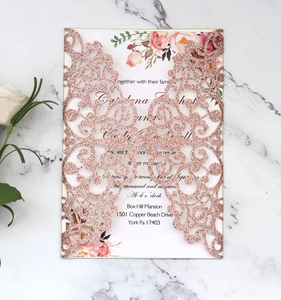 Detail of rose gold glitter laser cut wedding invitation on white marble surface
