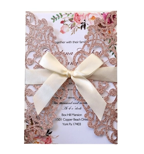 Detail of rose gold laser-cut wedding invitation with glitter texture and cream silk ribbon