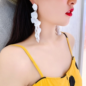 Detail of matte white multi-layer rose petal drop earrings worn with a summer outfit