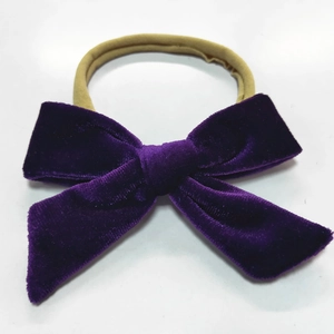 Close-up of a soft purple velvet bow attached to a stretchy khaki nylon baby headband