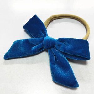 Detail of soft blue velvet bow baby headband with elastic nylon band on white background