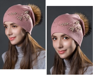 Gros plan sur les perles et strass du motif papillon sur un bonnet en maille rose chaud