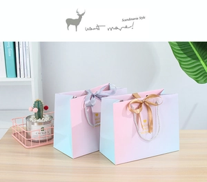 Detail of gradient pink and purple gift bag with satin bow and white woven handle