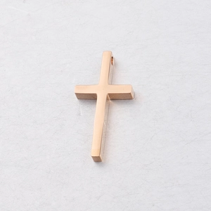 Polished rose gold stainless steel cross pendant on a textured grey surface