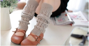 Detailed cable knit pattern on light gray leg warmers paired with brown Mary Jane shoes