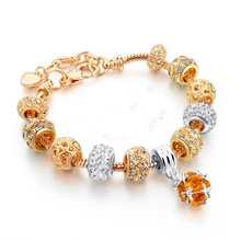 Detailed macro of gold and silver snake chain bracelet with orange faceted gemstone charm