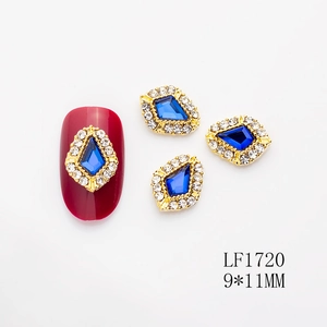 Detalle de adorno de lujo para uñas con corazón de gema azul y pedrería dorada