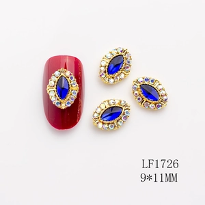Detalle de arte de uñas con gema marquesa azul y cristales sobre marco dorado lujo