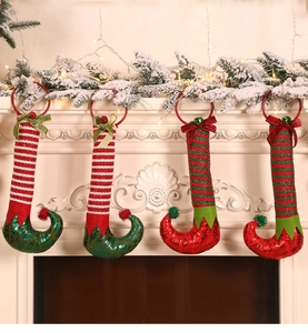 Close-up of sparkling sequined Christmas elf leg ornaments hanging on a white fireplace