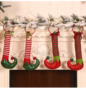 Close-up of festive Christmas elf boot ornaments with bells hanging on a white fireplace