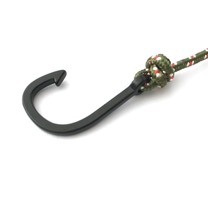 Macro detail of black metal fish hook anchor with red white and green woven rope