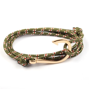 Detail of olive green braided rope bracelet featuring a golden fish hook anchor clasp