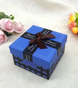 Dettaglio di una scatola regalo blu e nera con motivi a cuore e nastro di seta marrone