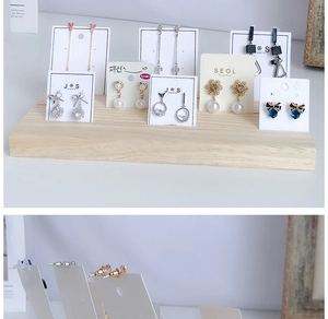 Detailed view of assorted earrings on white cards displayed on a tiered wooden jewelry stand