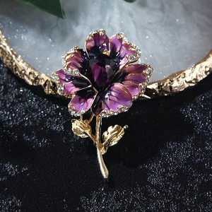 Detailed macro view of purple flower brooch with crystal droplets and gold plating
