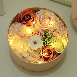 Romantic round gift box with pink soap roses, carnations, and warm LED fairy light decor