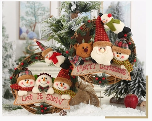 Detail of rattan Christmas wreaths featuring plush Santa and Snowman with merry banners
