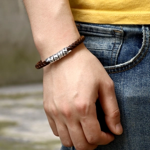 Men's brown braided leather bracelet with engraved silver beads on a male wrist