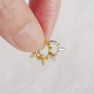 Close-up of S925 silver huggie hoop earrings with spikes and beads in gold and silver