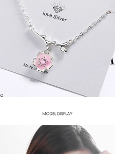 Close-up of pink cherry blossom pendant necklace with silver chain and gemstones