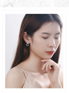 Close-up of star-shaped floral earrings with sparkling white zircons on ear lobe