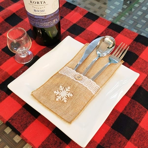 Linen Christmas cutlery holder with white snowflake and lace on red plaid tablecloth