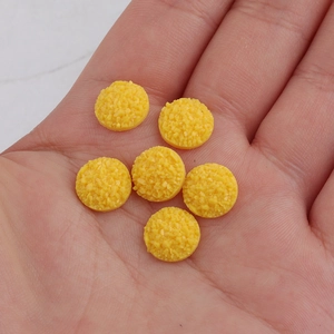 Macro shot of 10mm yellow resin druzy cabochons in hand for size comparison