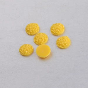Detailed view of 10mm yellow resin cabochons with textured surface and smooth flat back