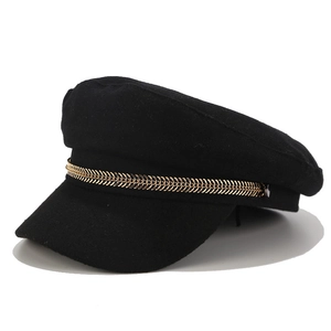 Detail of black wool newsboy hat featuring a premium golden metallic chain accent