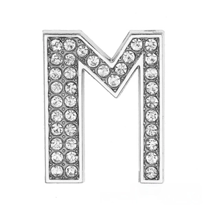 Close-up of silver-tone letter M charm accessory with pave-set sparkling crystals