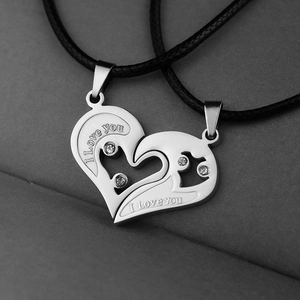 Close-up of interlocking heart-shaped couple necklaces with crystals and I Love You engraving