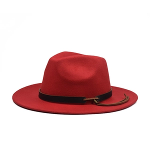 Detailed view of red wool fedora with black belt trim and brown leather tassel