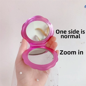Detail of shell-shaped folding mirror showing normal and magnifying glass surfaces